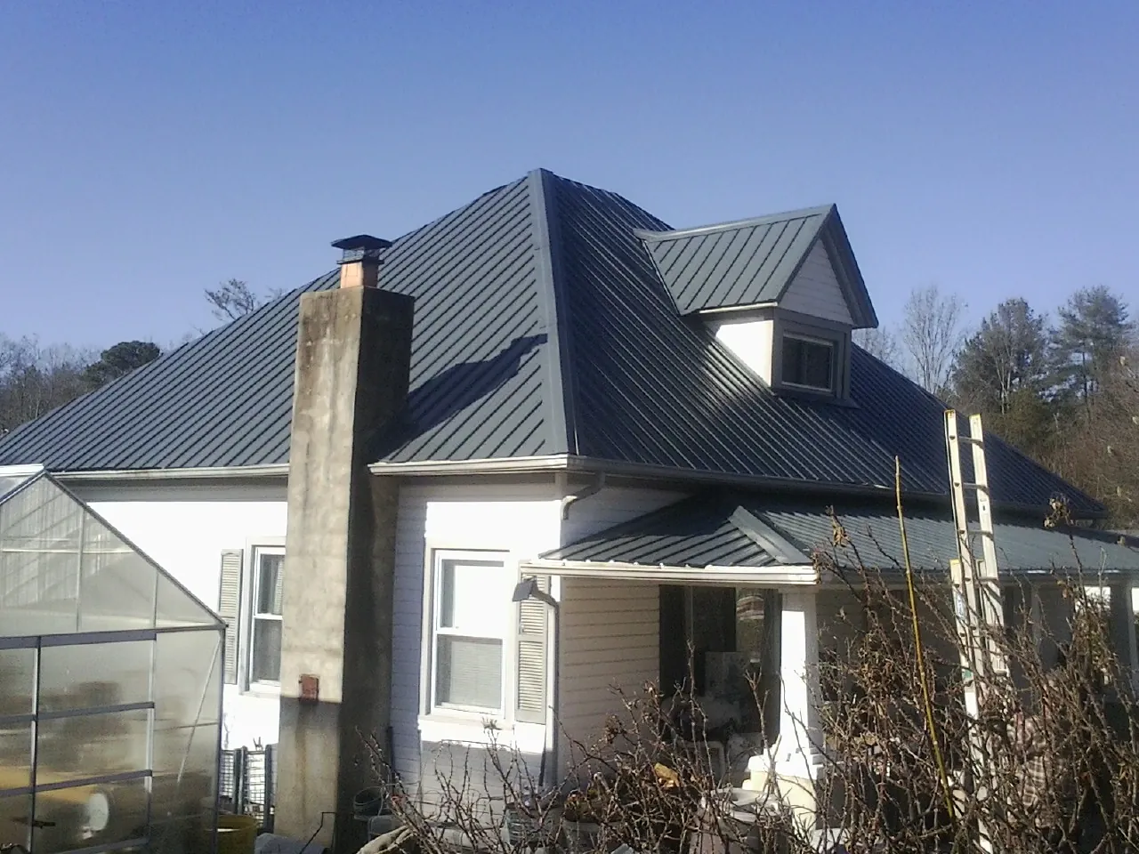 Dark blue standing seam metal roof on a white farmhouse with dormer — Slate & Tile Roof Repair by Roofing Brothers in Castalian Springs