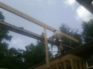 Carpenter setting a ridge beam over a new addition frame — Ice Dam Removal by Roofing Brothers in Castalian Springs
