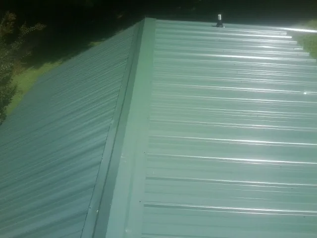 New green metal panels meeting at the ridge of a roof — Flat Roof Repair work by our crew in Castalian Springs