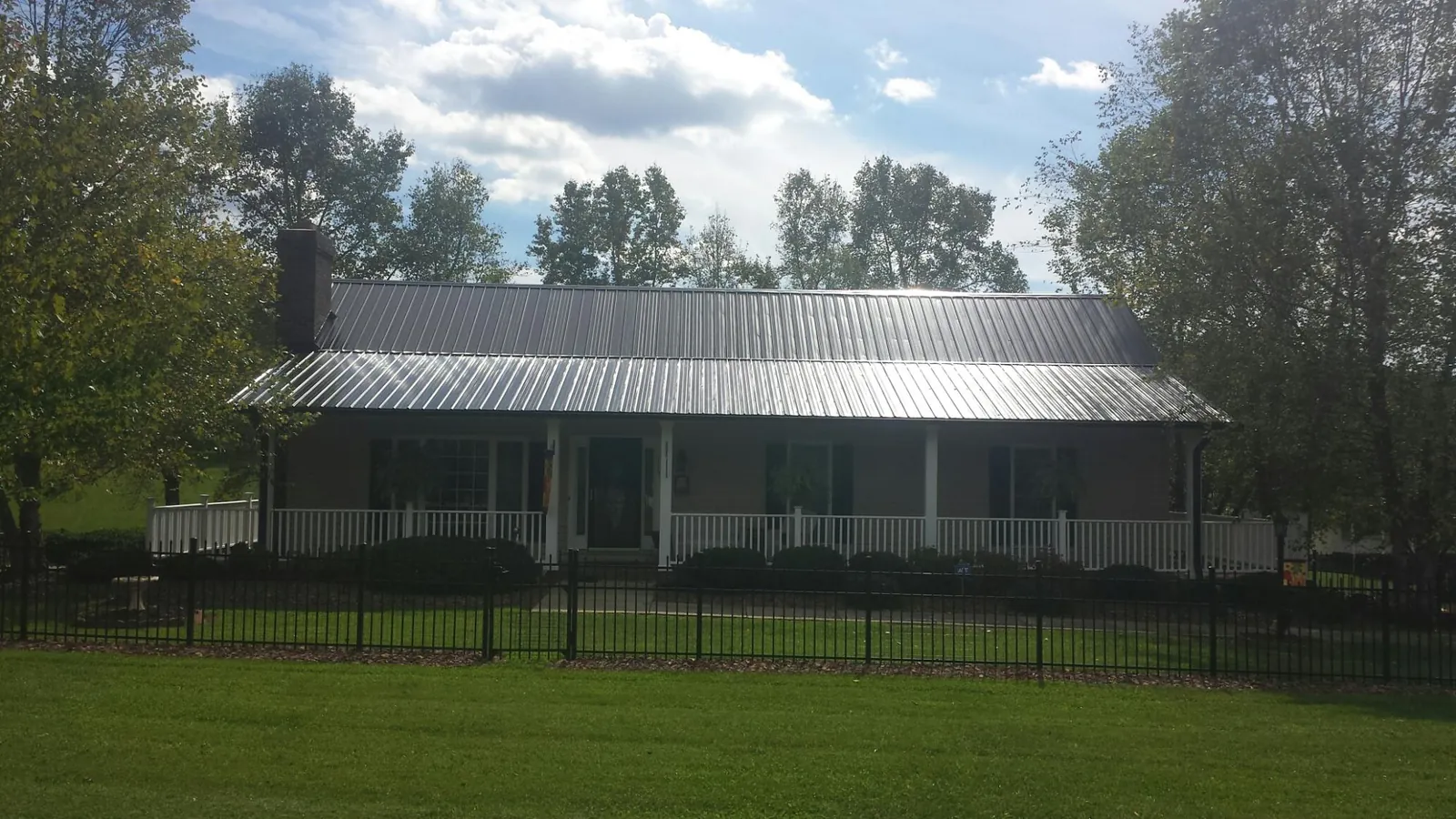 Gray metal roof on a brick ranch with a full width front porch — Gutter Guard Installation work by our crew in Castalian Springs