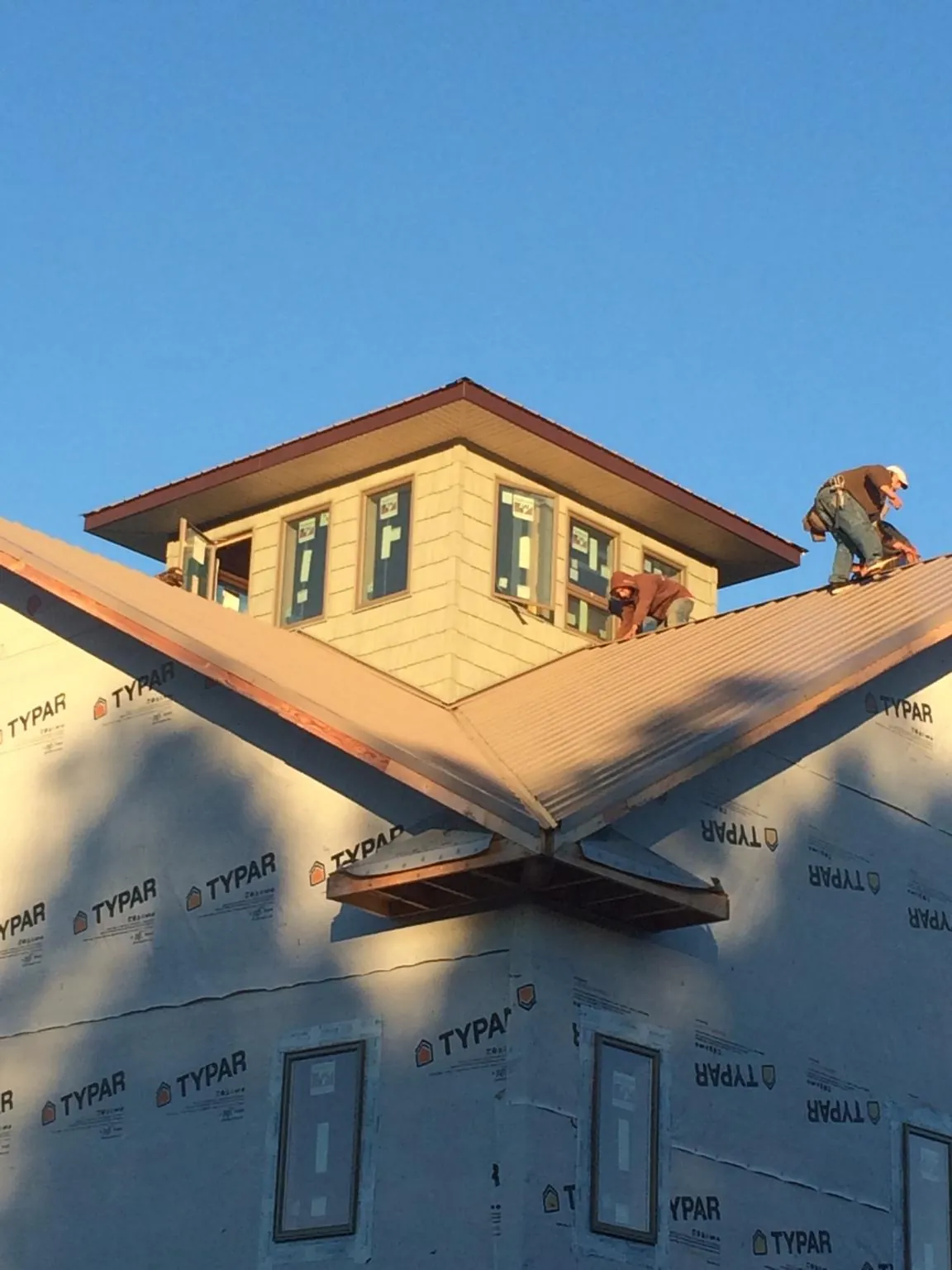 Roofers working around a rooftop cupola on a new metal roof at sunset — Roof Waterproofing in Castalian Springs by Roofing Brothers